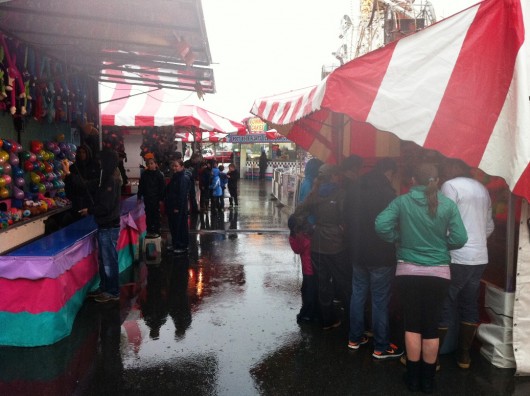 Fair attendees cluster under awnings to keep out of the rain Thursday.