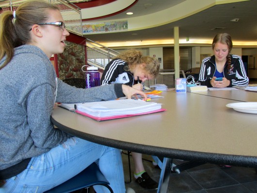 Natasha Bolshakoff, Tabitha Gordanier, and Katie Powers work on homework at Sitka High School. Because they often miss school to travel for games, the team has gotten used to doing their homework on road.