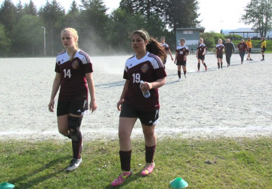 Angel Spurgeon and Teiara Hayes lead their team off the field after the first game against Sitka, which Ketchikan won 5-0.