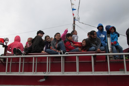 Children sit on top of a fire truck in the parade.