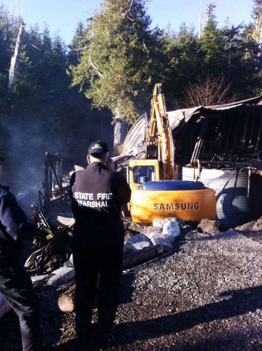This Alaska State Trooper photo shows the State Fire Marshal at the scene of Wednesday's Blackberry Lane house fire. An excavator is helping authorities search the debris for evidence. 