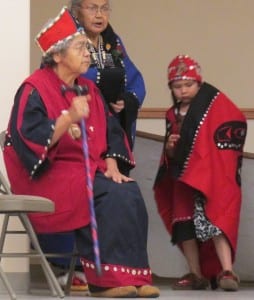A young dancer is seen learning from her elders. 