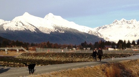 Dogs and their owners enjoy a snowless walk on a trail bordering Juneau's airport Dec. 29. Show has accumulated on nearby mountains. (Ed Schoenfeld, CoastAlaska News)