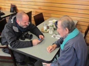 Photographer Danny Goldfield shows centenarian Henry Neligan some apps on his smartphone while talking at the Ketchikan Indian Community cafeteria. 