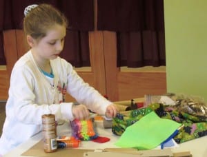 A young girl makes a cat toy for felines at the animal shelter.
