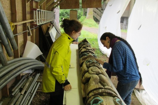 From left, conservation intern AnnMarie Guerin and Alaska State Museum Conservationist Ellen Carlee inspect a pole, donated to Ketchikan's Totem Heritage Center by Tsimpshian master carver David Boxley. (Photo by Leila Kheiry) 