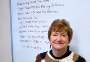Southeast Senior Services Director Marianne Mills poses with a partial list of other organizations it works with. (Photo by Ed Schoenfeld,/CoastAlaska News)