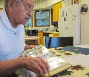 Elder Fred John looks through a photo album of old pictures from his time traveling and singing with a church group. (Photo by Leila Kheiry)