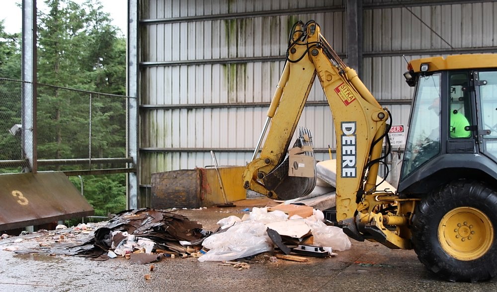 Jim Walters, with Waste Connections, operates a front-end loader to push trash aboard a container van, staged on the lower level of the Sitka Waste Transfer Station. (Robert Woolsey/KCAW)